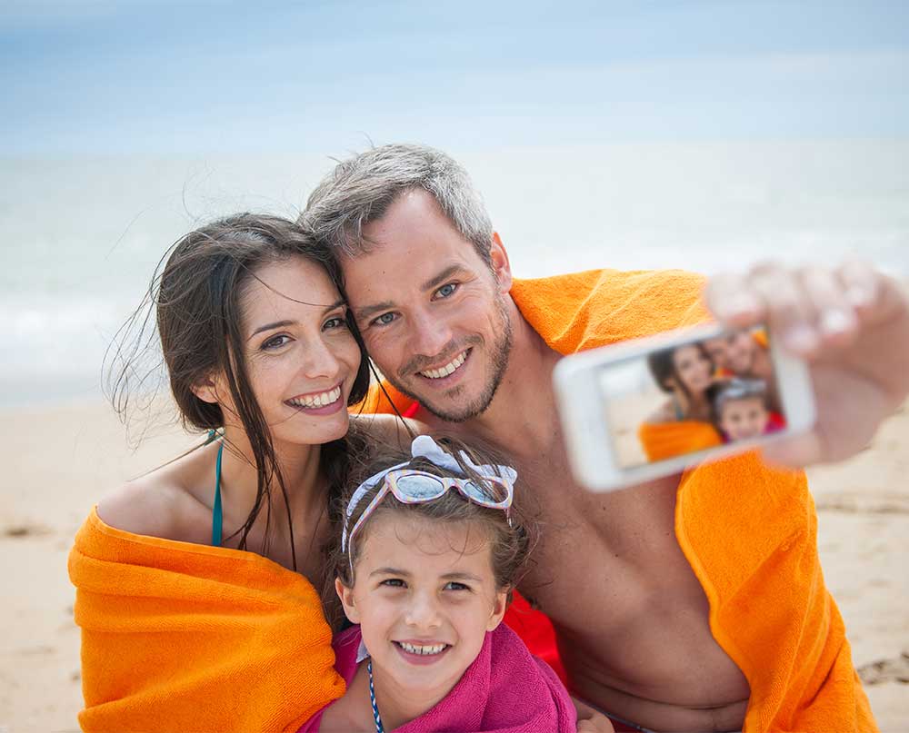 family taking a beach selfie