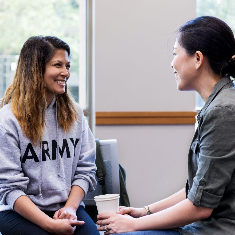 woman wearing Army sweatshirt having coffee with another woman